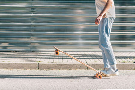 unrecognizable man with casual clothes lifting up an skateboard with his feetの写真素材