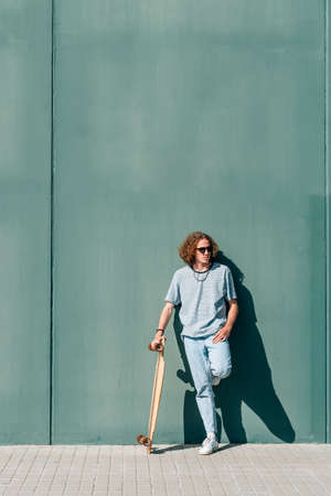 Young skateboarder resting near a green wallの写真素材