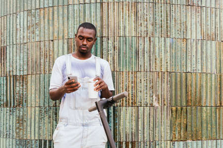 portrait of an afro american young man waiting in the street while using his phone