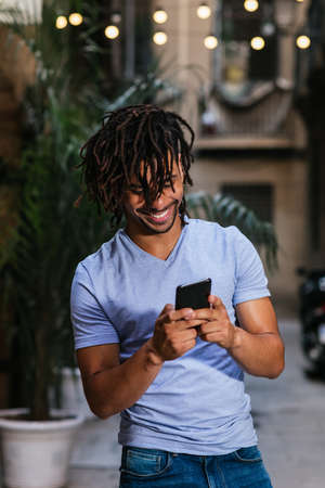 vertical portrait of a young latin man using his phone in the streets at eveningの写真素材
