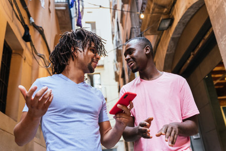 latin and african friends commenting about social networks content on the phone and smilingの写真素材