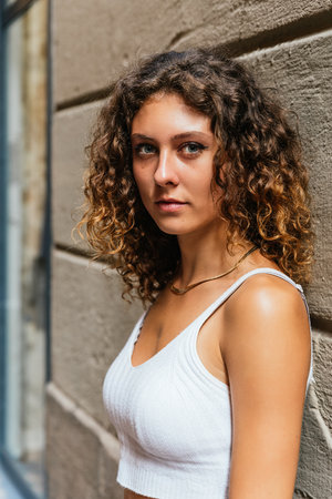 vertical portrait of an attractive young woman with long curly hair looking at cameraの写真素材