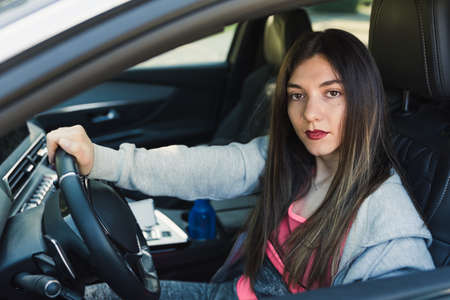 caucasian young young woman looking from the window of her carの写真素材