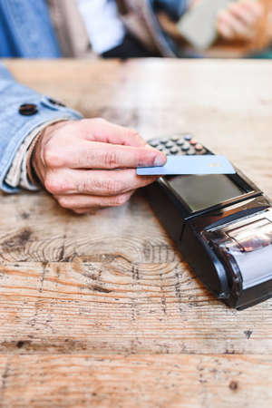 Crop customer paying for order in cafe with credit cardの写真素材