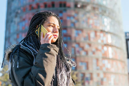 Sad Hispanic woman talking on smartphone in city