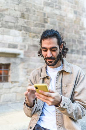 Man browsing smartphone near shabby building