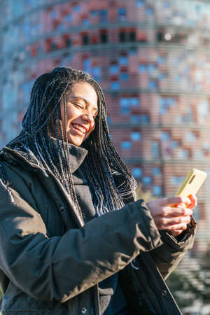 Content Hispanic woman surfing smartphone on street