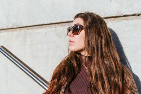 Woman in sunglasses near concrete wallの写真素材