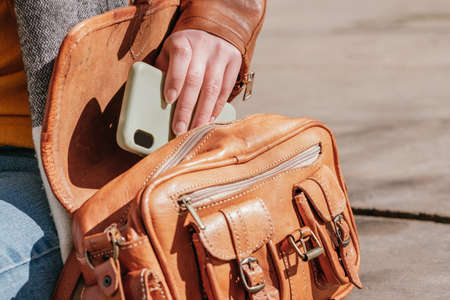 Unrecognizable woman putting smartphone in handbagの写真素材