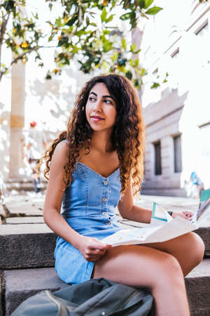 Young indian woman with city map sitting on steps