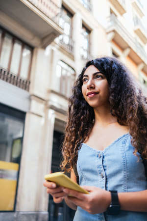 Attractive brunette walking the city with backpack and yellow phoneの写真素材