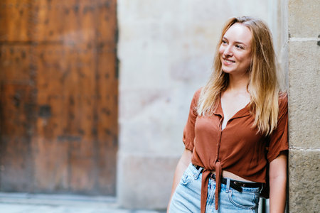blonde caucasian female tourist leaning on a wall of Barcelona old town