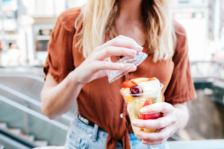 unrecognizable female tourist opening a cup of sliced fresh fruitsの写真素材
