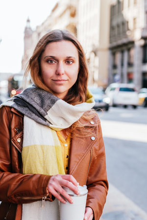 caucasian blonde young woman with take-away coffee in the streetの写真素材