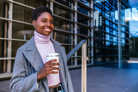 Black woman with hot drink in downtownの写真素材