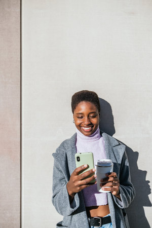 Black woman reading news on cellphone in morning