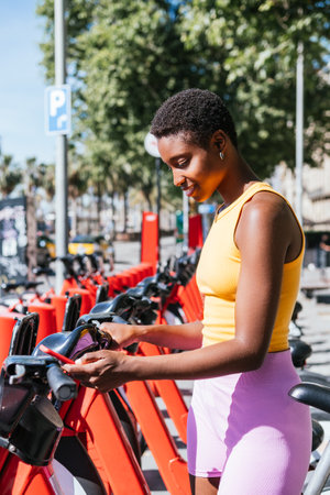 african woman using public bike rental system with phone application