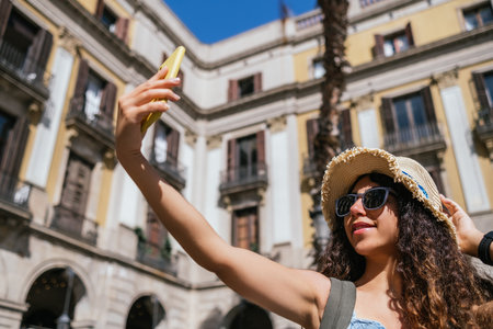 young indian travel blogger shooting a self picture at Barcelona old town squareの写真素材