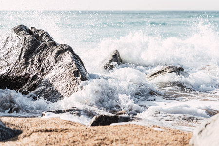 Sea crashing on rocky coast on sunny day