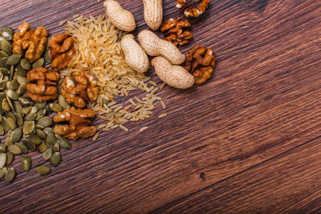 Assorted nuts on a wooden surface. Peanuts, almonds, hazelnuts, pumpkin seeds, walnuts. Top view with copy space.の写真素材