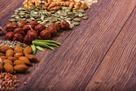 Assorted nuts on a wooden surface. Peanuts, almonds, hazelnuts, pumpkin seeds, walnuts. Top view with copy space.の写真素材