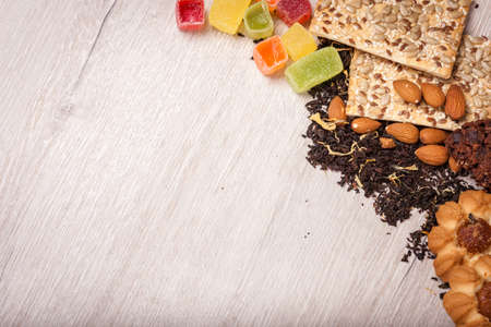 The composition of the tea on a wooden surface. scattering of tea, almond and hazelnut. Green, black...