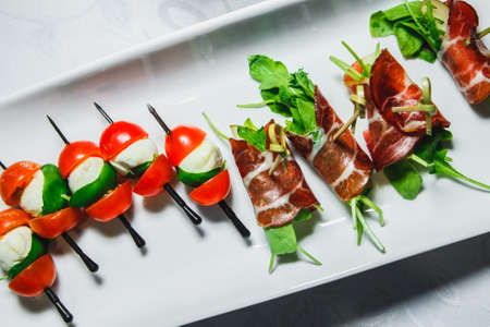 snacks with meat and vegetables. Tapas with salmon and pickled cucumber. Prosciutto with pears and arugula.の写真素材