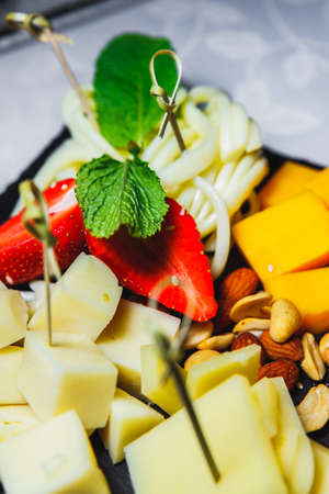 snacks with meat and vegetables. The set of cheese.Tapas with strawberries and cheese, salmon with pickled cucumber. Prosciutto with pears and arugula.の写真素材