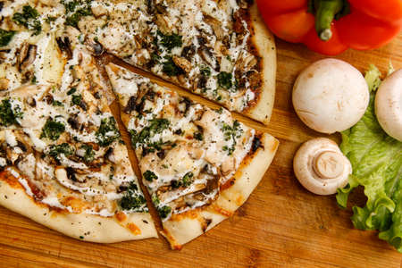 Fresh pizza with tomatoes, cheese and mushrooms on wooden table closeupの写真素材