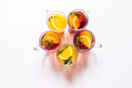 a glass of beautiful bright cocktail on a wooden surface decorated with fruits, berries, leaf of mint and basil at bar counter background.の写真素材