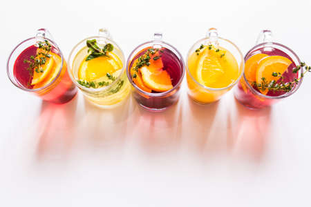 a glass of beautiful bright cocktail on a wooden surface decorated with fruits, berries, leaf of mint and basil at bar counter background.の写真素材
