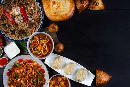 The concept of middle East cuisine. Assorted Uzbek food set, pilaf, samsa, lagman, manti, shurpa eastern restaurant concept, Uzbek food. pilaf or plov from lamb served in cast iron cookware.の写真素材