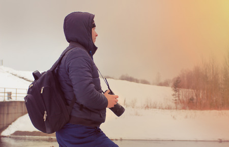 Young photographer smitrit forward on the banks of the dam. A traveler on the background of winter...