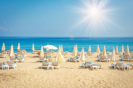 Resort hotel beach on sea. Summer vacation on tropical beach. Sunbeds and umbrellas on sea beach.の写真素材