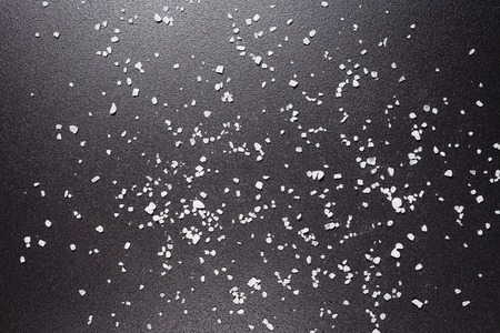 Sea salt is scattered on black background