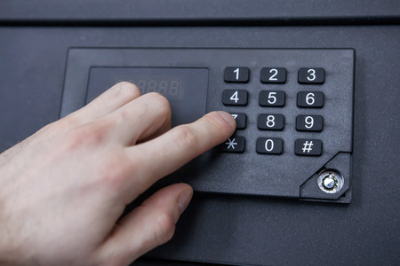 man enters code from safe close-up. Hand, safe, numbers. Safely store money and jewelry at homeの写真素材