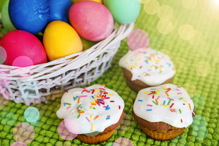 Easter background. Colorful Easter eggs and sweet cupcakes on a green background. Spring Christian...
