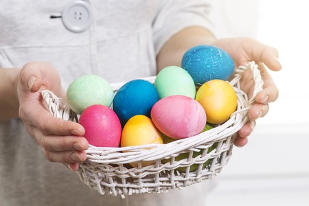 Easter concept. A woman holds basket with colorful colored eggs for religious Easter holiday. Easter eggs in basketの写真素材