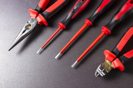 Tools electrician screwdrivers, pliers, platypuses on black background