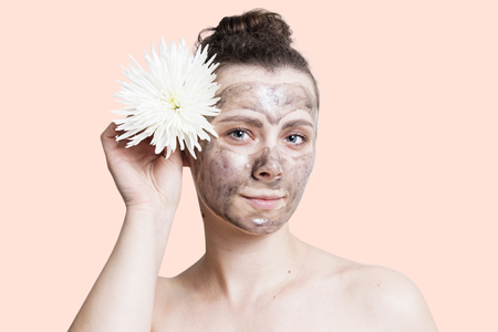Skincare concept. Girl with facial cosmetic black mask and with white flower.の写真素材