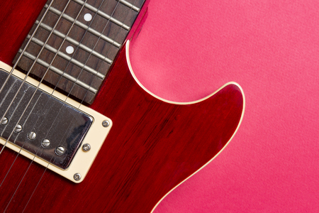 Close-up of red electric guitar on pink background. Musical concept of guitar musicの写真素材