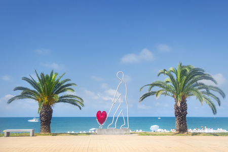 Modern sculpture with heart on beach of Batumi. Symbol of Batumi, Georgia. Quay Batumi near the sea, palm trees and sculpture of a man with a heartの写真素材