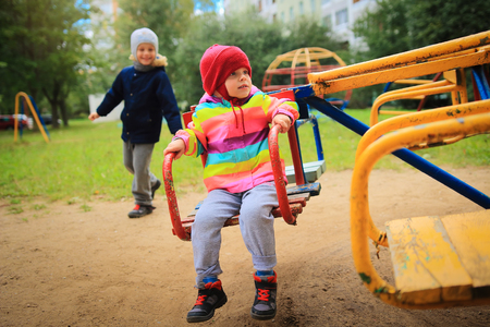 Children ride on the carousel in the playground. Playing children. Little cute babes ride on a swingの写真素材