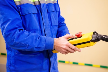 Worker with remote control of crane in industrial storageの写真素材