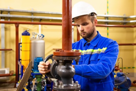 Technician employee opens gate valve on industrial pipeline. Services works on gas and oil station....