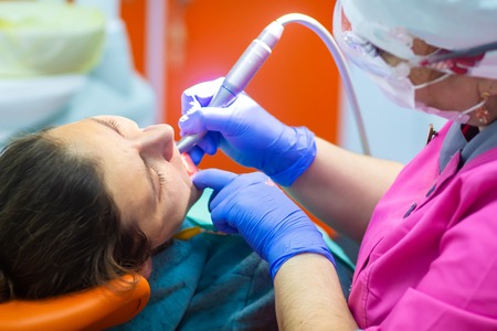 Dentist drills patient teeth. Girl treats teeth in dental clinic. Dentist with tools treats teethの写真素材