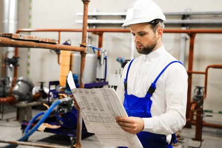 Engineer with blueprints on industrial plant. Manager in industry. Service maintenance on oil...