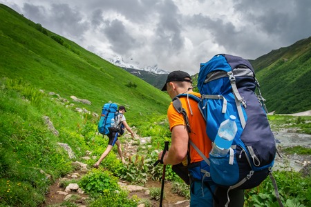 Tourists hiking in mountains. Man with backpack hike in mountain pathの写真素材