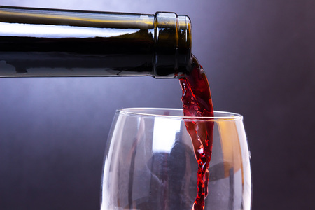 Red wine pouring from bottle to glass