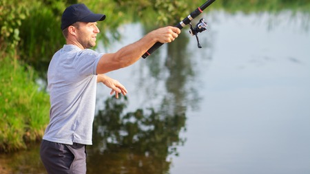 Fisherman on lakeside. Man with fishing rodの写真素材